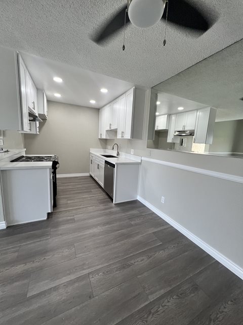 A kitchen with a white counter and a grey floor.